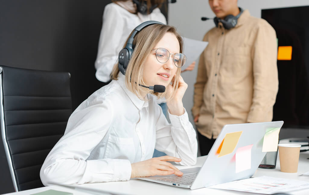 Mitarbeiterin der Servicezentrale mit Headset am Laptop